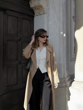 a lady in a light brown mulberry silk trench coat  with black pants